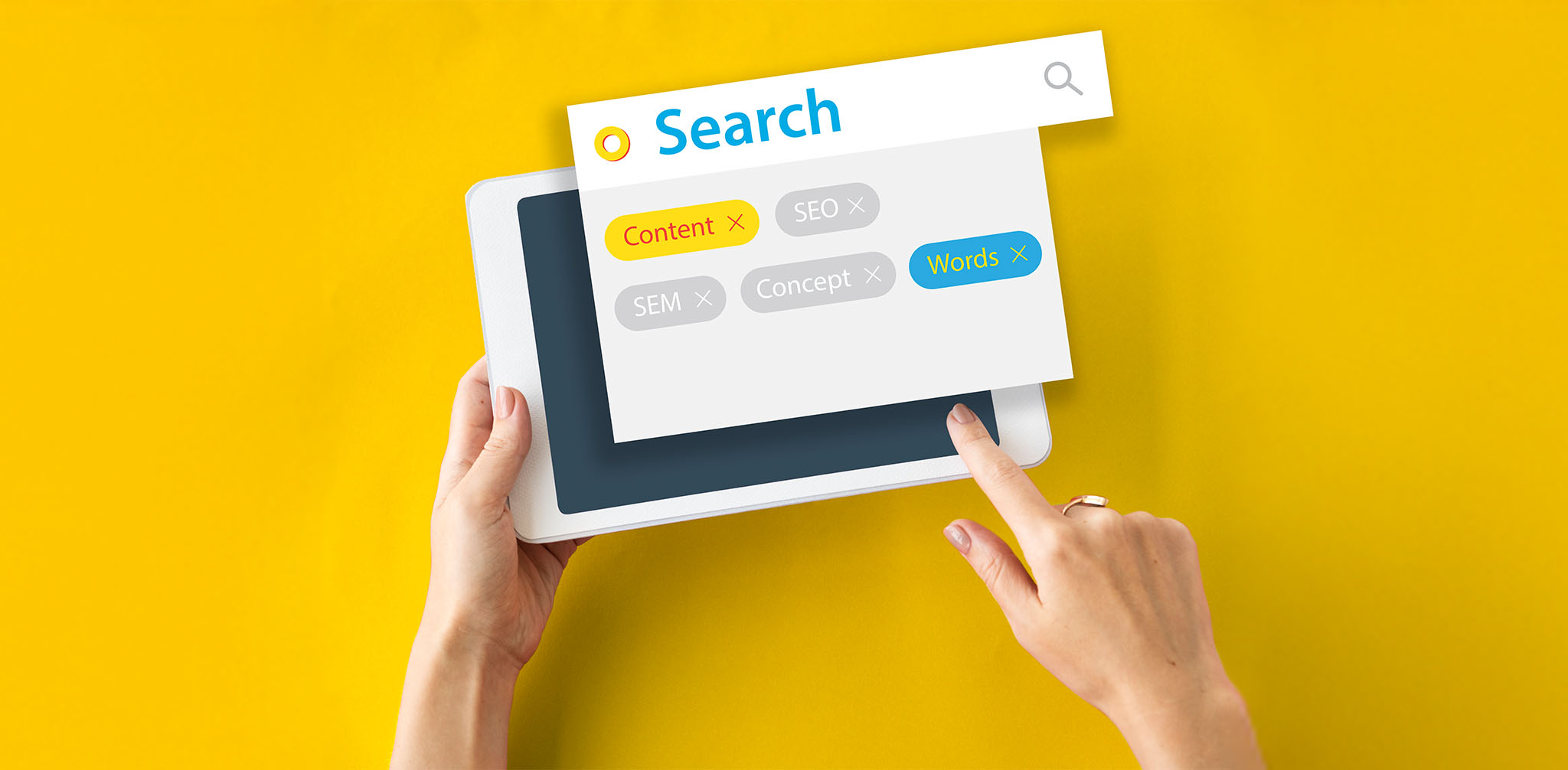 Eine Nahaufnahme von Händen, die einen weißen Tablet-Computer auf einem leuchtend gelben Hintergrund halten. Über dem Tablet schwebt ein Suchfeld mit dem Wort "Search" (Suchen) und einer Lupe. Darunter sind verschiedene Suchbegriffe als farbige Tags angeordnet, darunter "Content" (Inhalt) in Gelb, "Words" (Wörter) in Türkis sowie "SEO", "SEM" und "Concept" (Konzept) in Grau.